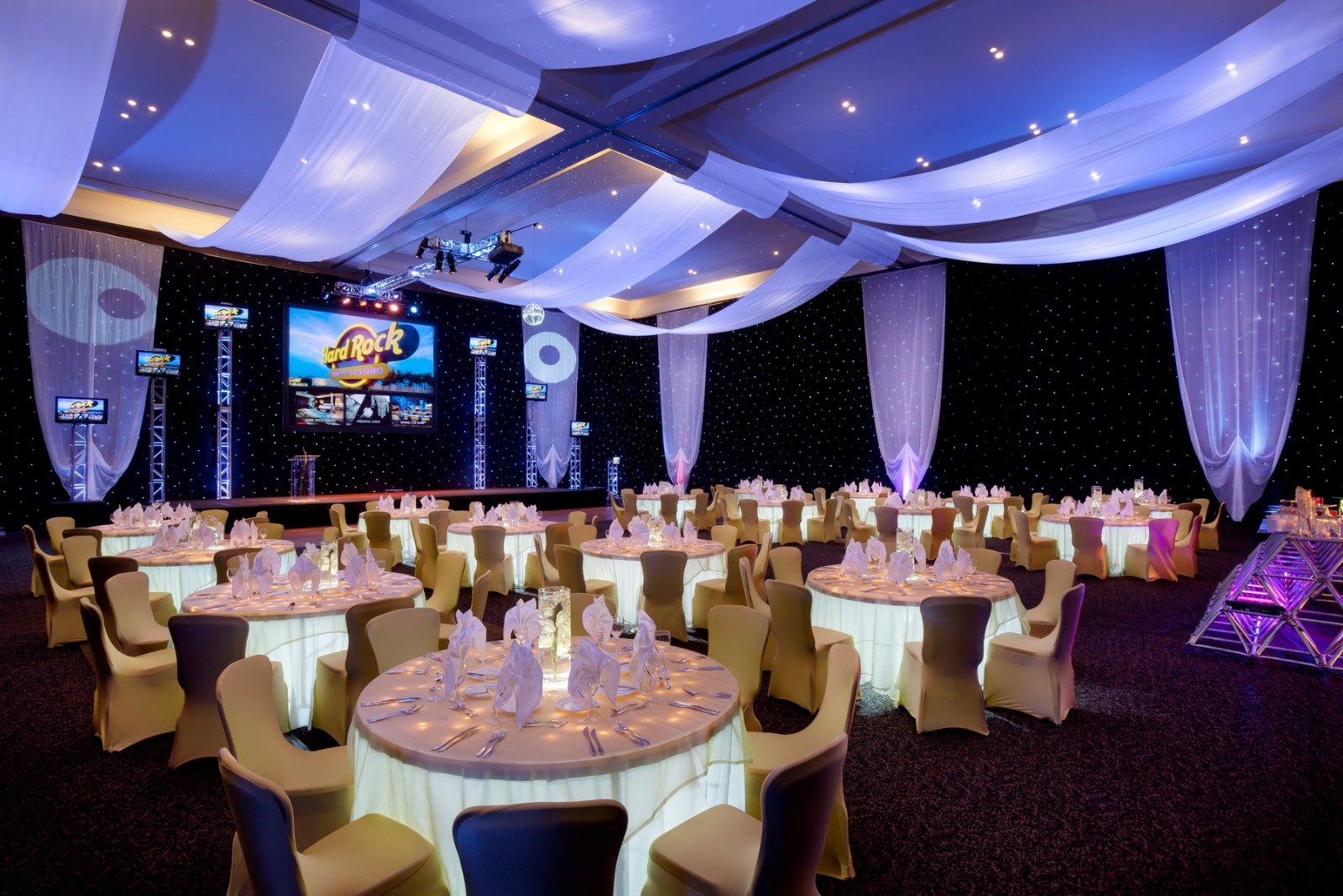 An elegant ballroom wedding setup at Hard Rock Punta Cana with round tables and soft lighting